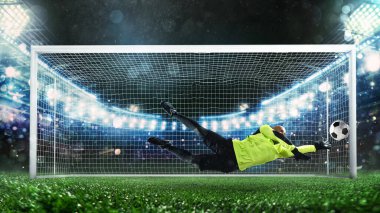 Futbol kalecisi, floresan üniformalı, harika bir kurtarış yapıyor ve stadyumdaki maçta gol atmaktan kaçınıyor.