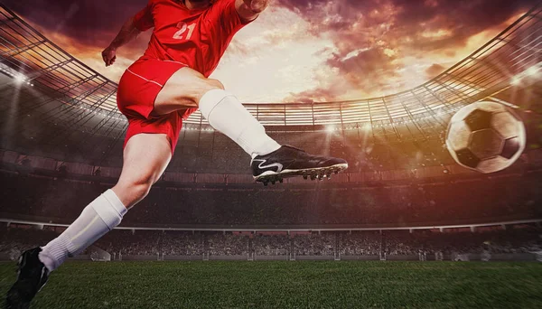 Close-up de uma cena de futebol durante um jogo com o jogador em um uniforme vermelho chutando a bola com poder — Fotografia de Stock