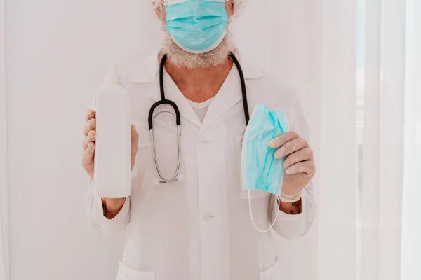 Dokter toont een desinfecterende gel en een gezichtsmasker voor covid-19 virus — Stockfoto