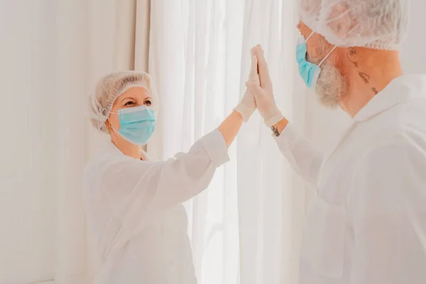 Ärzte mit Maske und Gesichtsschutz geben einander eine 5 mit der Hand — Stockfoto
