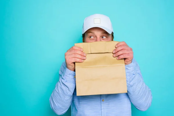 El repartidor esconde su cara con un paquete de comida — Foto de Stock