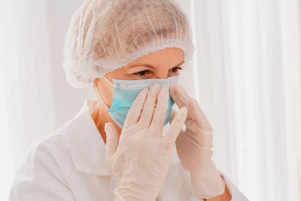 Läkare justera ansiktsmask för att skydda sig mot covid-19 virus — Stockfoto