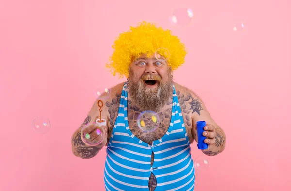 Удивительный человек с желтым париком в голове играть с мылом пузырьков — стоковое фото
