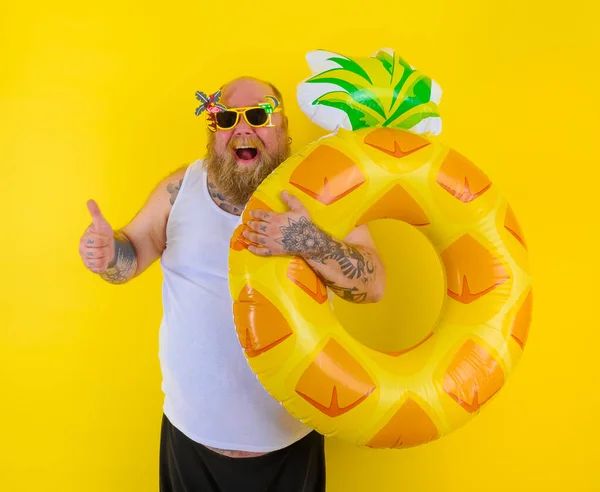 Kafasında peruk olan şişman mutlu adam bir donut cankurtaranıyla yüzmeye hazır. — Stok fotoğraf