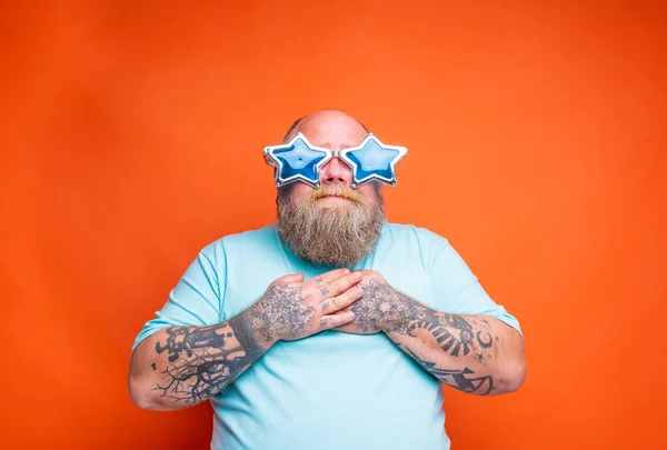 Tłuszcz zdumiony mężczyzna z brodą, tatuażami i okularami przeciwsłonecznymi jest czymś zaskoczony — Zdjęcie stockowe