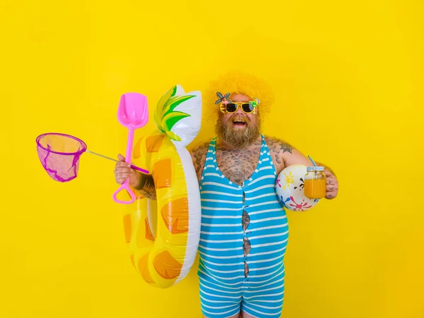 Fat happy man with wig in head is ready to swim with a donut lifesaver — Stock Photo, Image