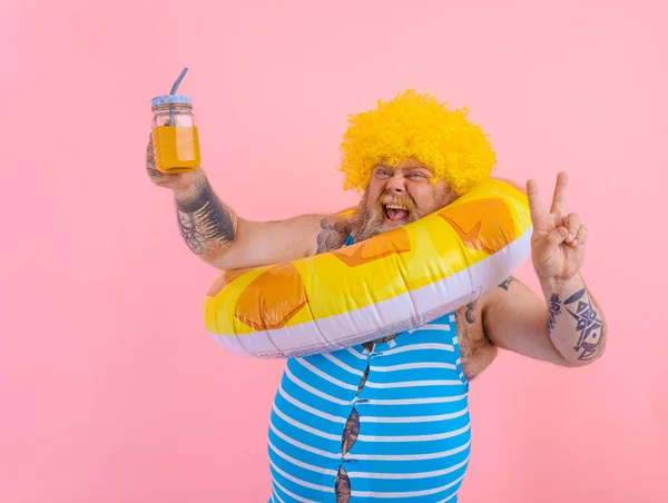 Grasso uomo felice con parrucca in testa è pronto a nuotare con un salvagente ciambella — Foto Stock