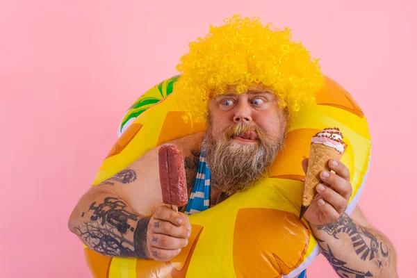 Fat man with beard and wig eats a popsicle and an icecream — Stock Photo, Image