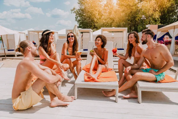 Grupa przyjaciół w stroju kąpielowym pije koktajl w miejscu na plaży — Zdjęcie stockowe