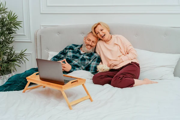 Чоловік і дружина дивитися фільм на ліжку і їсти попкорн — стокове фото