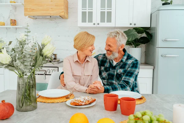 Чоловік і дружина обіймаються вдома під час сніданку — стокове фото