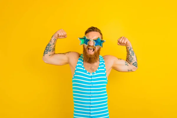 Uomo con barba, tatuaggi e costume da bagno mostra il suo muscolo — Foto Stock