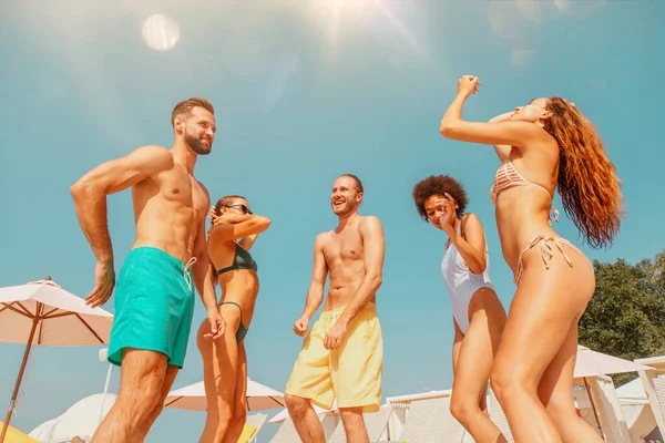 Grupo de amigos en traje de baño bailan música en una piscina — Foto de Stock