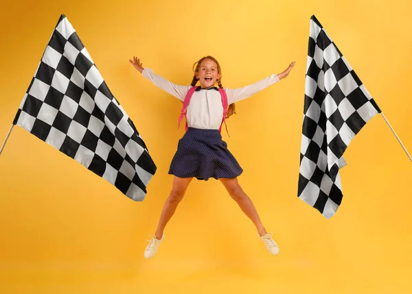 Chica joven estudiante salta alto feliz por la promoción y llega a la bandera. Fondo amarillo —  Fotos de Stock