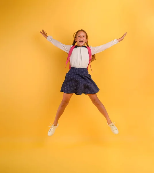 Студент молодої дівчини стрибає високо щасливим для просування. Жовтий фон — стокове фото