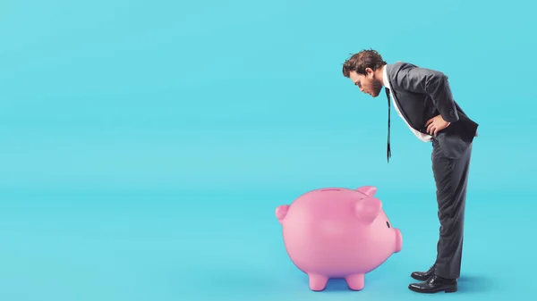 Man looks inside the piggy bank looking for money — Stock Photo, Image