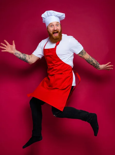 Felice chef con barba e grembiule rosso salta — Foto Stock