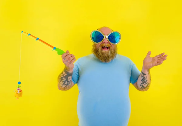 Tlustý muž s vousy a slunečními brýlemi bavte se s rybářskou prutem — Stock fotografie