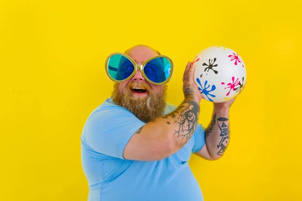 Grasso uomo con barba e occhiali da sole divertirsi con una palla — Foto Stock