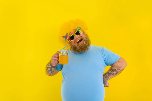 Grasso uomo felice con parrucca in testa e occhiali da sole beve un succo di frutta — Foto Stock