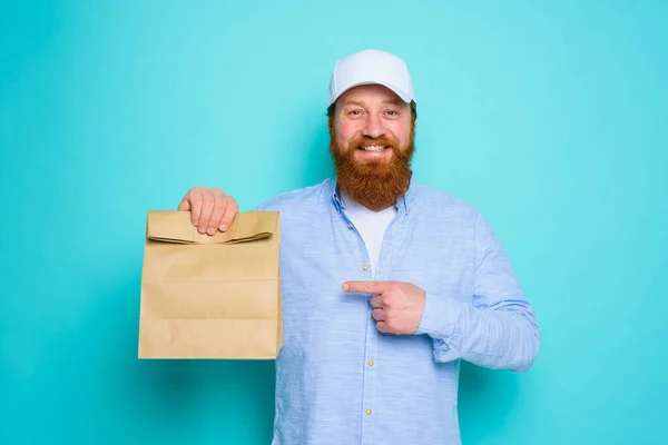 Livreur avec une expression heureuse est prêt à livrer un paquet alimentaire — Photo