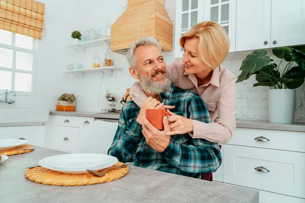Чоловік і дружина обіймаються вдома під час сніданку — стокове фото