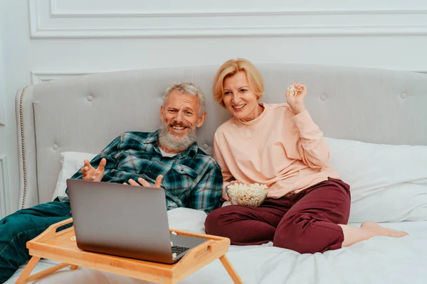 Чоловік і дружина дивитися фільм на ліжку і їсти попкорн — стокове фото