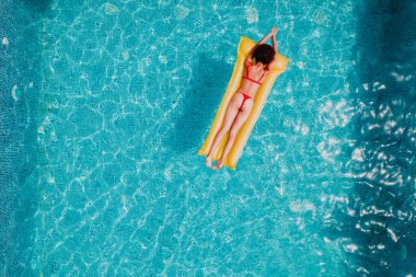 Yüzme havuzunda bronzlaşan mayo giymiş kız.