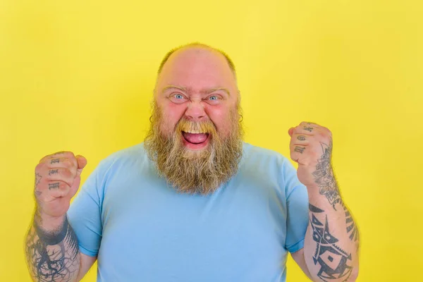 Счастливый человек с бородой и татуировками делает победный жест руками — стоковое фото