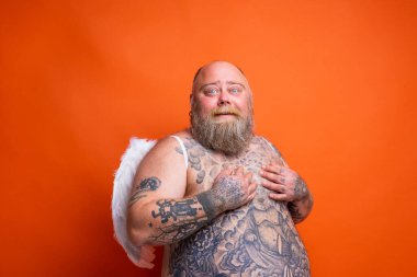 Sakallı, dövmeli ve kanatlı şişman adam melek gibi davranıyor.