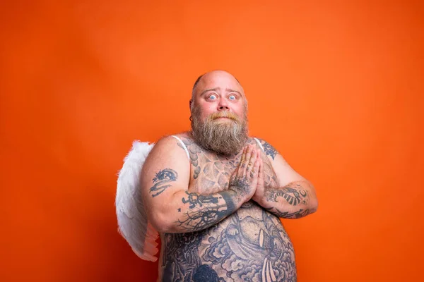 Gordo hombre asustado con barba, tatuajes y alas actúa como un ángel — Foto de Stock