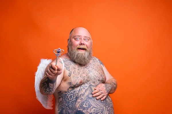 Dikke gelukkige man met baard, tatoeages en vleugels gedraagt zich als een magische fee — Stockfoto