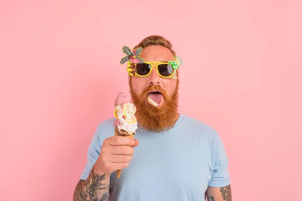Głodny człowiek z brodą i tatuażami zjada duże lody — Zdjęcie stockowe