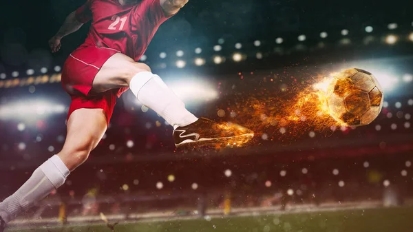 Крупный план футбольной сцены в ночном матче с игроком в красной форме, пинающим огненный мяч с силой — стоковое фото