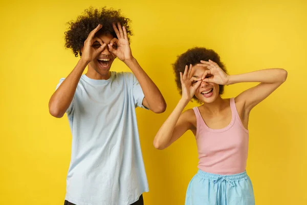 Joyeux couple blague en faisant des lunettes avec leurs mains — Photo