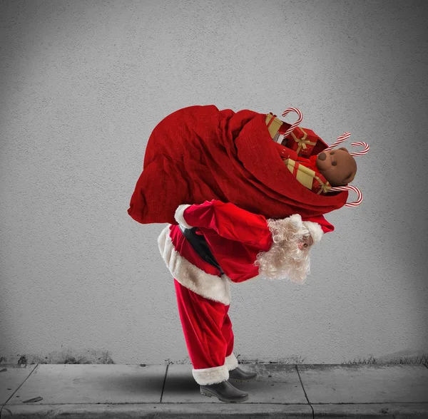 圣诞老人背着沉重的礼物袋 — 图库照片