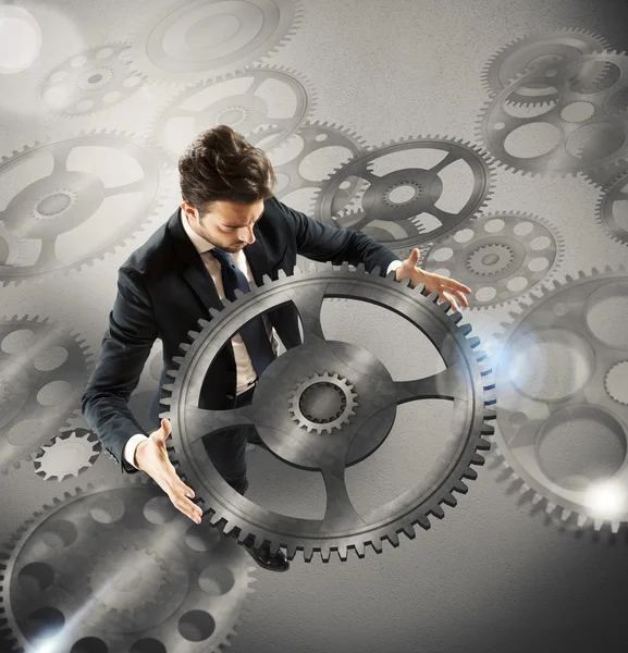 Businessman holds a piece of gear — Stock Photo, Image