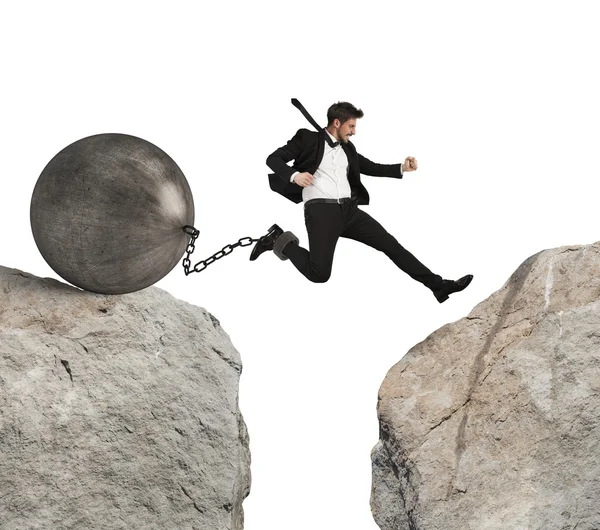 Businessman jumping with ball tied to foot — Stock Photo, Image