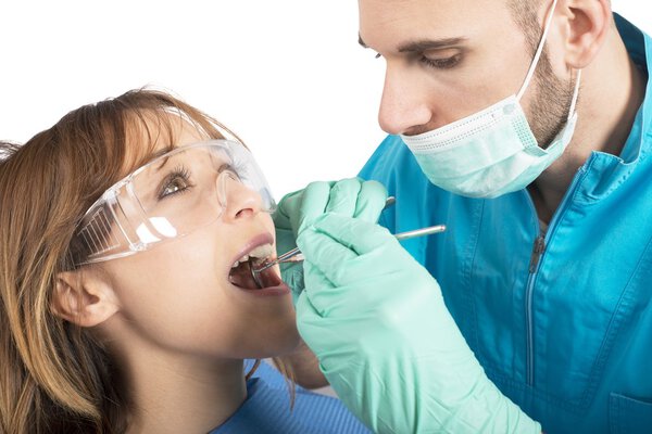 Стоматолог очищает зубы своего пациента
