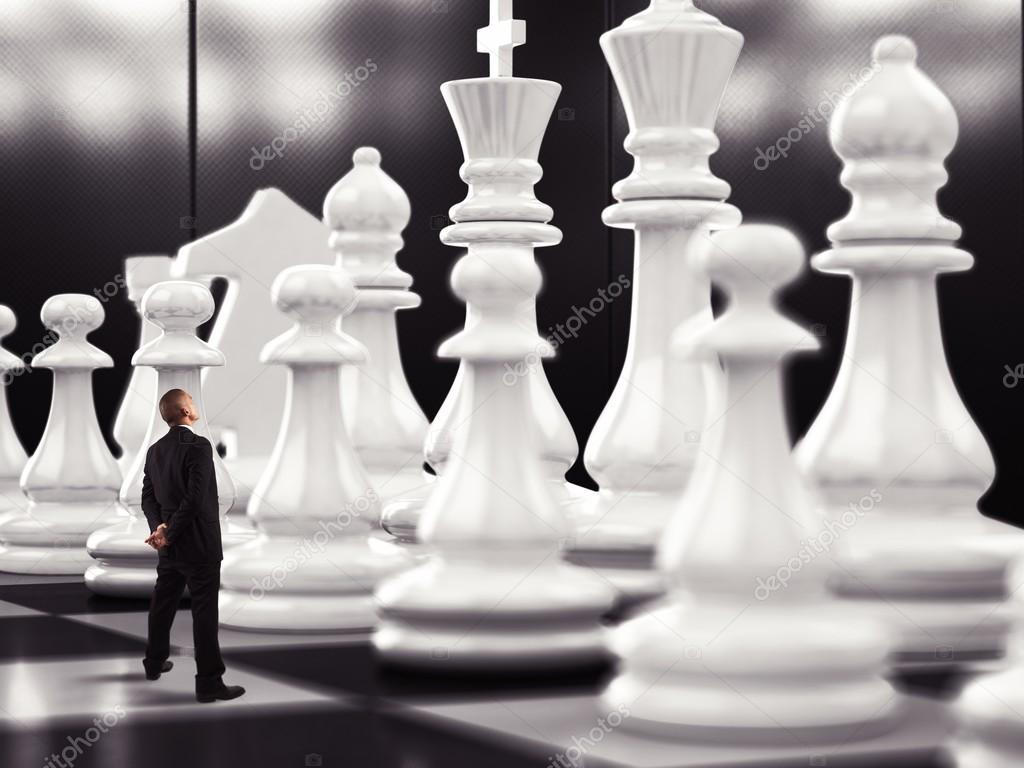 Businessman looks up to chess pawn