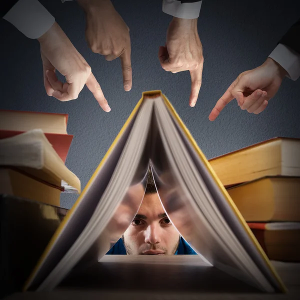 Student boy hides behind books — Stockfoto