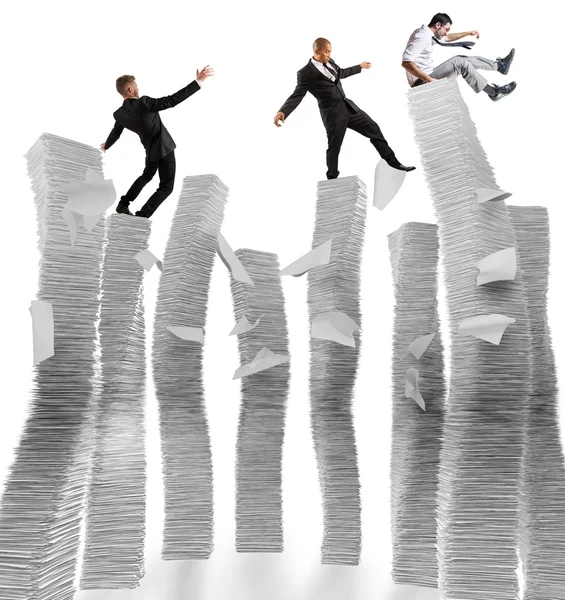 Businessmen on unstable piles of paper — Stock Photo, Image