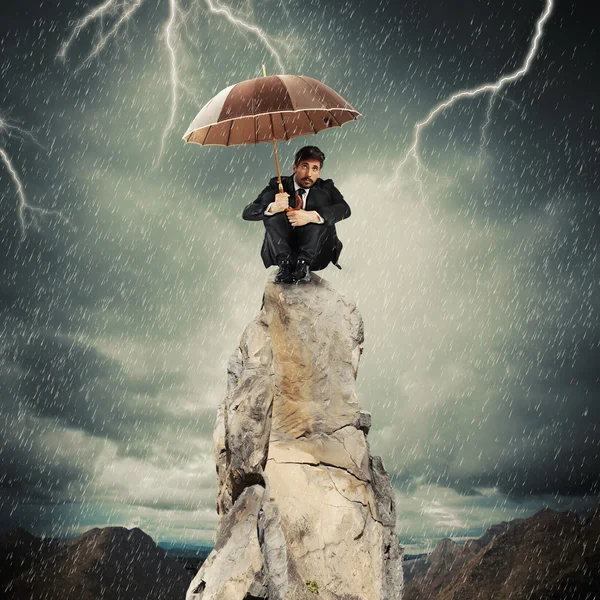 Hombre de negocios con paraguas en la parte superior de roca — Foto de Stock