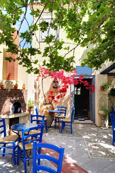 Die Amphore mit Blumen und traditionellen griechischen Tisch und Stühlen — Stockfoto