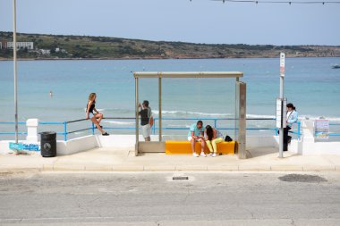 Mellieha, Malta - 20 Nisan: Otobüs istasyonu ve turistler üzerinde 20 Nisan 2015 Mellieha, Malta beach yakınındaki. Daha sonra 1,6 milyon turist Malta 2015 yılında ziyaret bekleniyor.