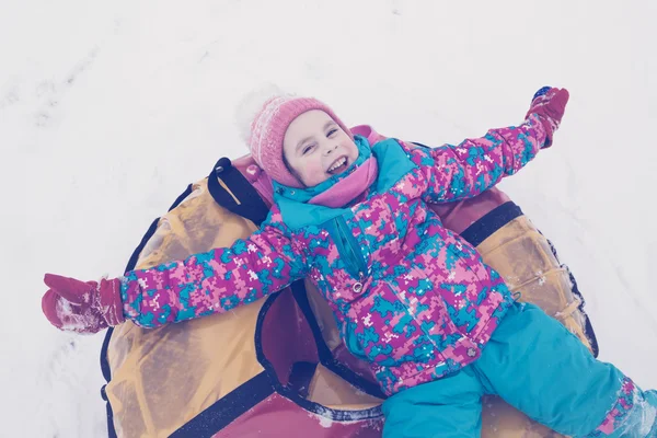 Söta unge ridning snow tube vinterdag. — Stockfoto