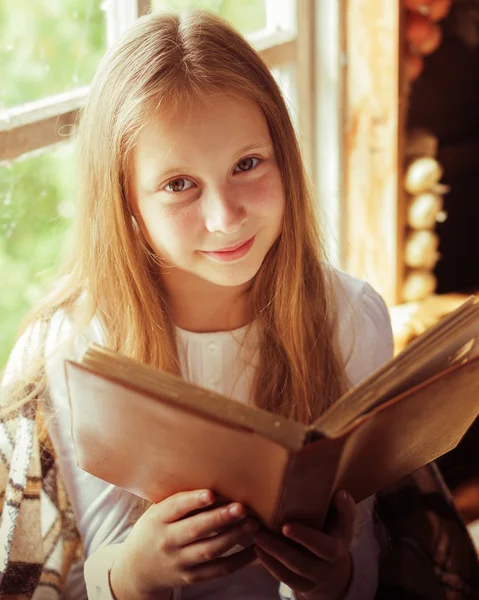 Byn tjej med en bok av fönstret. — Stockfoto