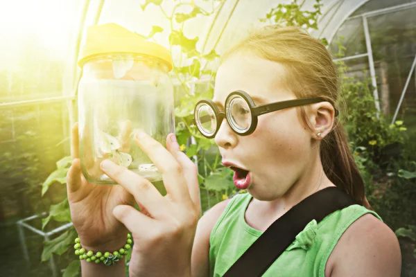 Grappig meisje met bril en vlinder in een pot. — Stockfoto