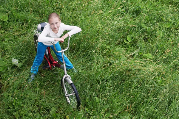 Bambino in bicicletta guida attraverso l'erba . — Foto Stock