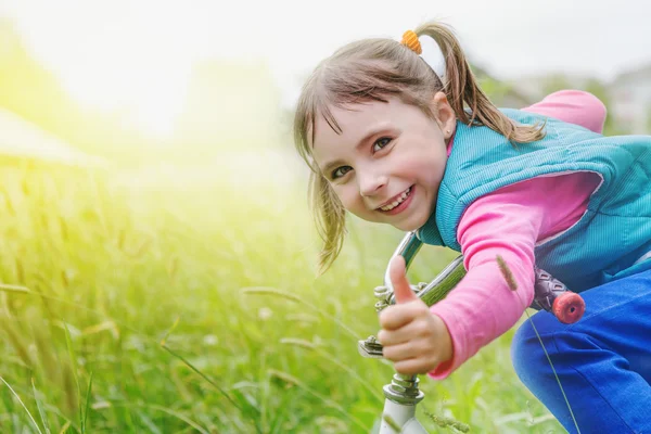 Bambino in bicicletta guida attraverso l'erba . — Foto Stock